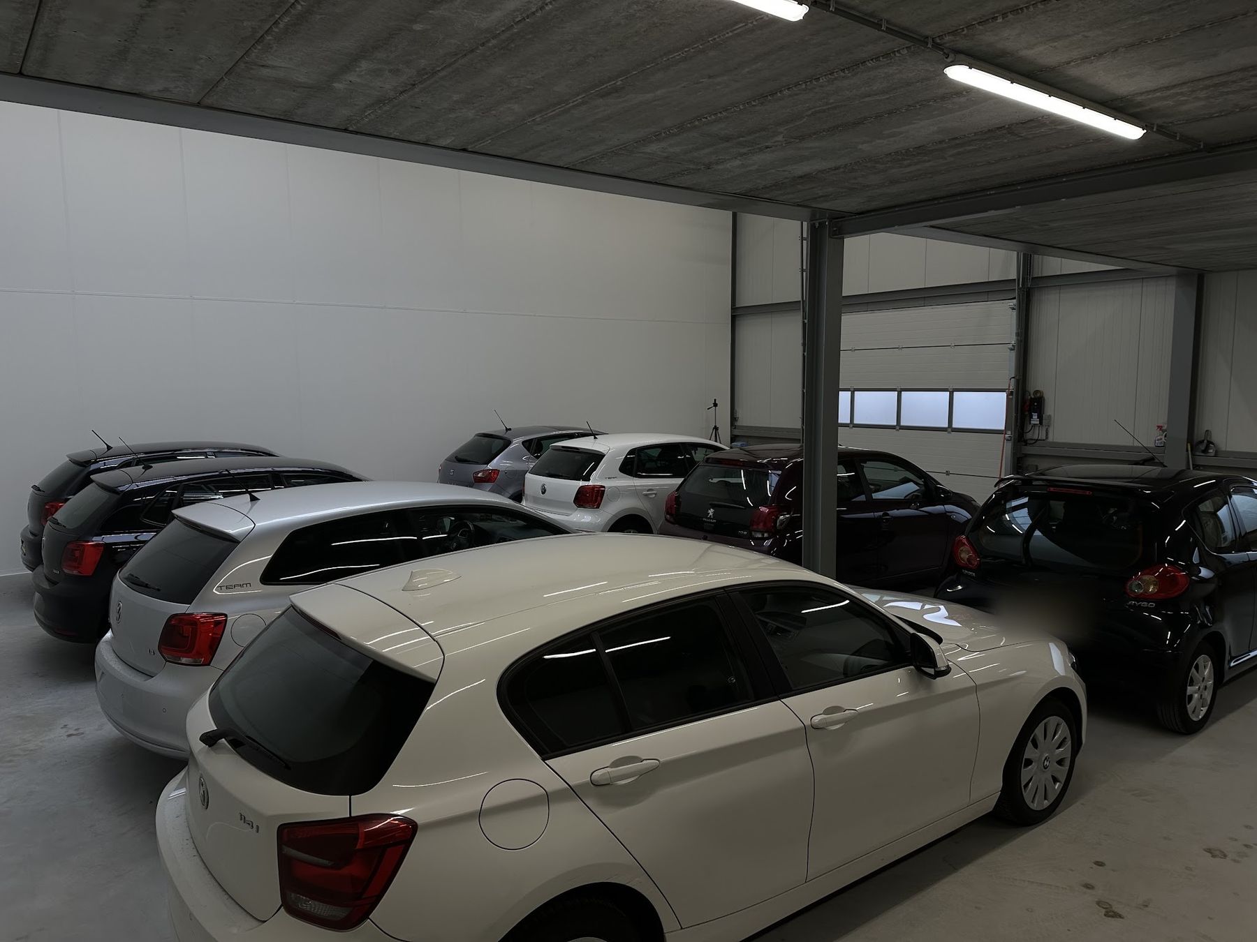 Occasions binnen in de hal van Next Ride Automotive: een BMW, Volkswagens, een Seat, een Peugeot en een Toyota